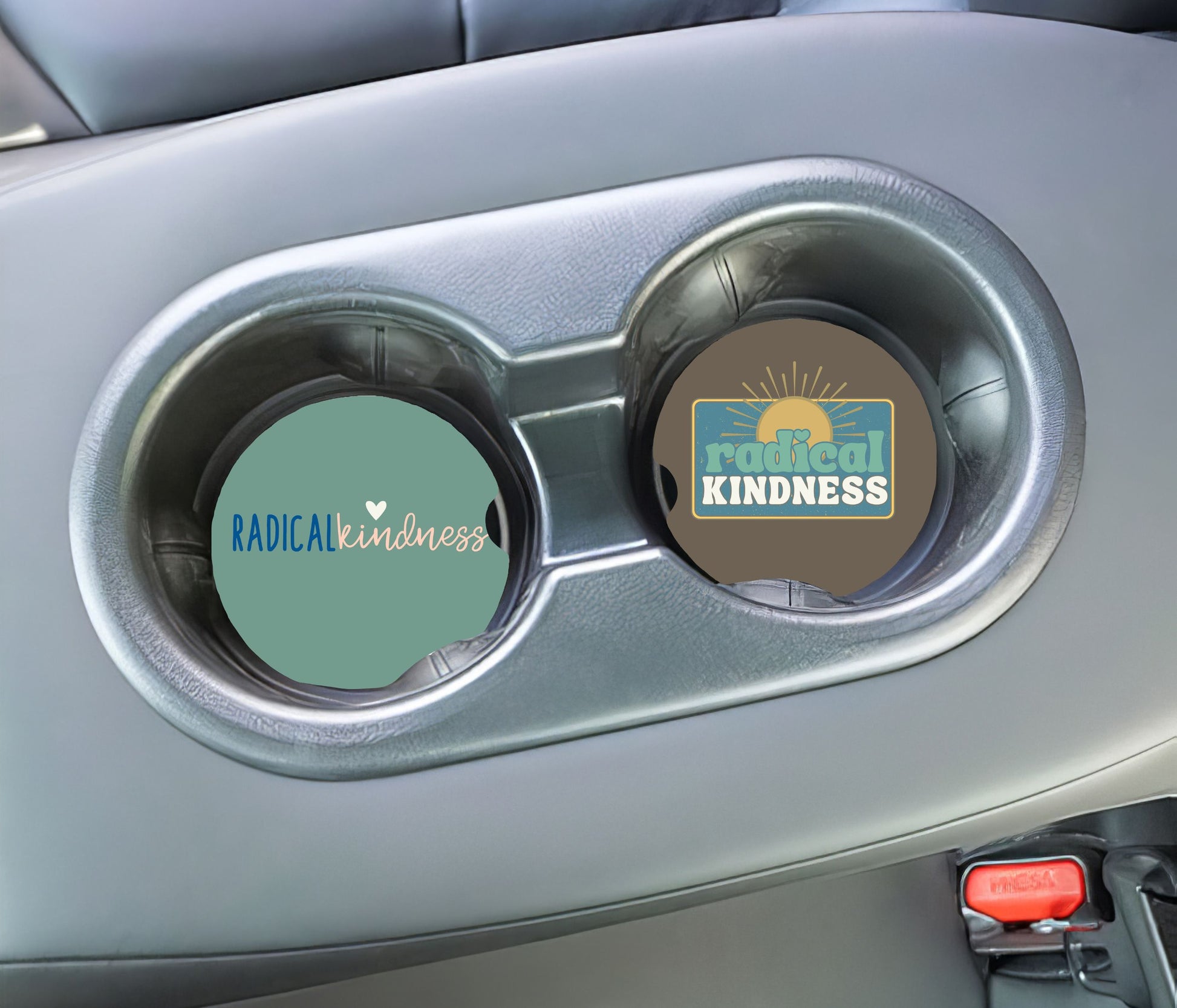 Two car cup holders with 'Radical Kindness' coasters inside a vehicle.